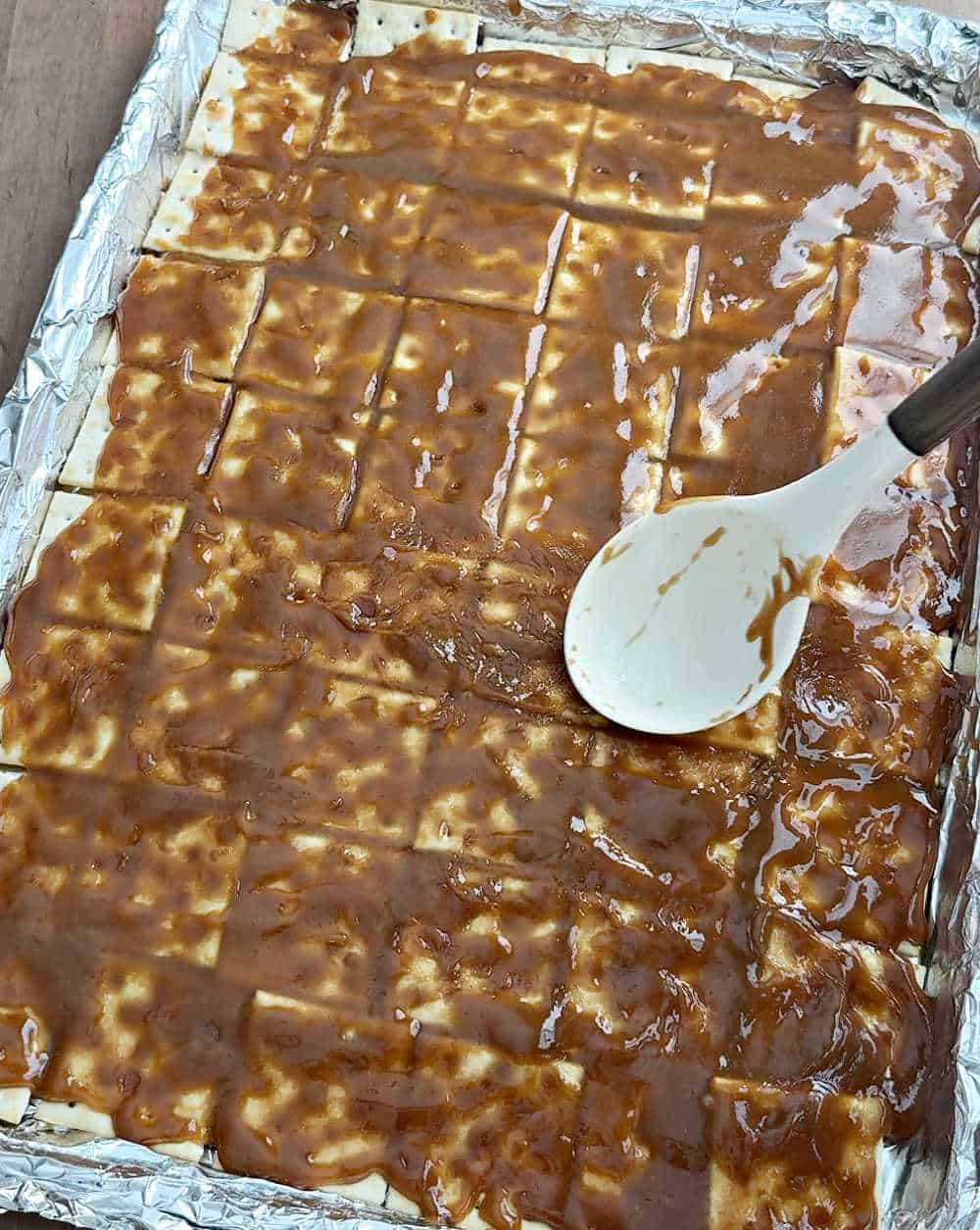 spreading toffee on top of crackers.