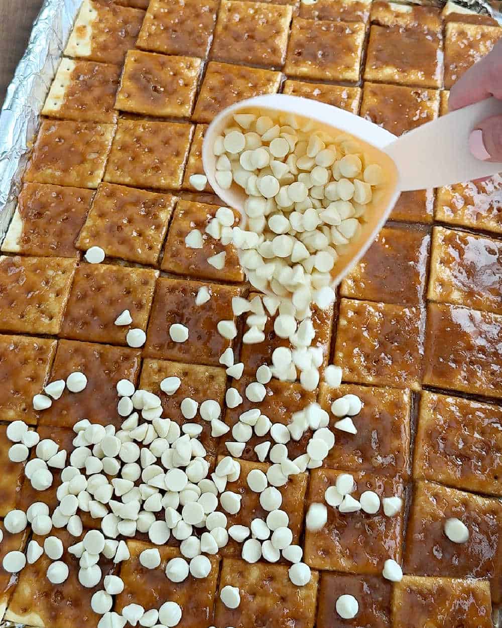 sprinkling white chocolate chips on crackers.