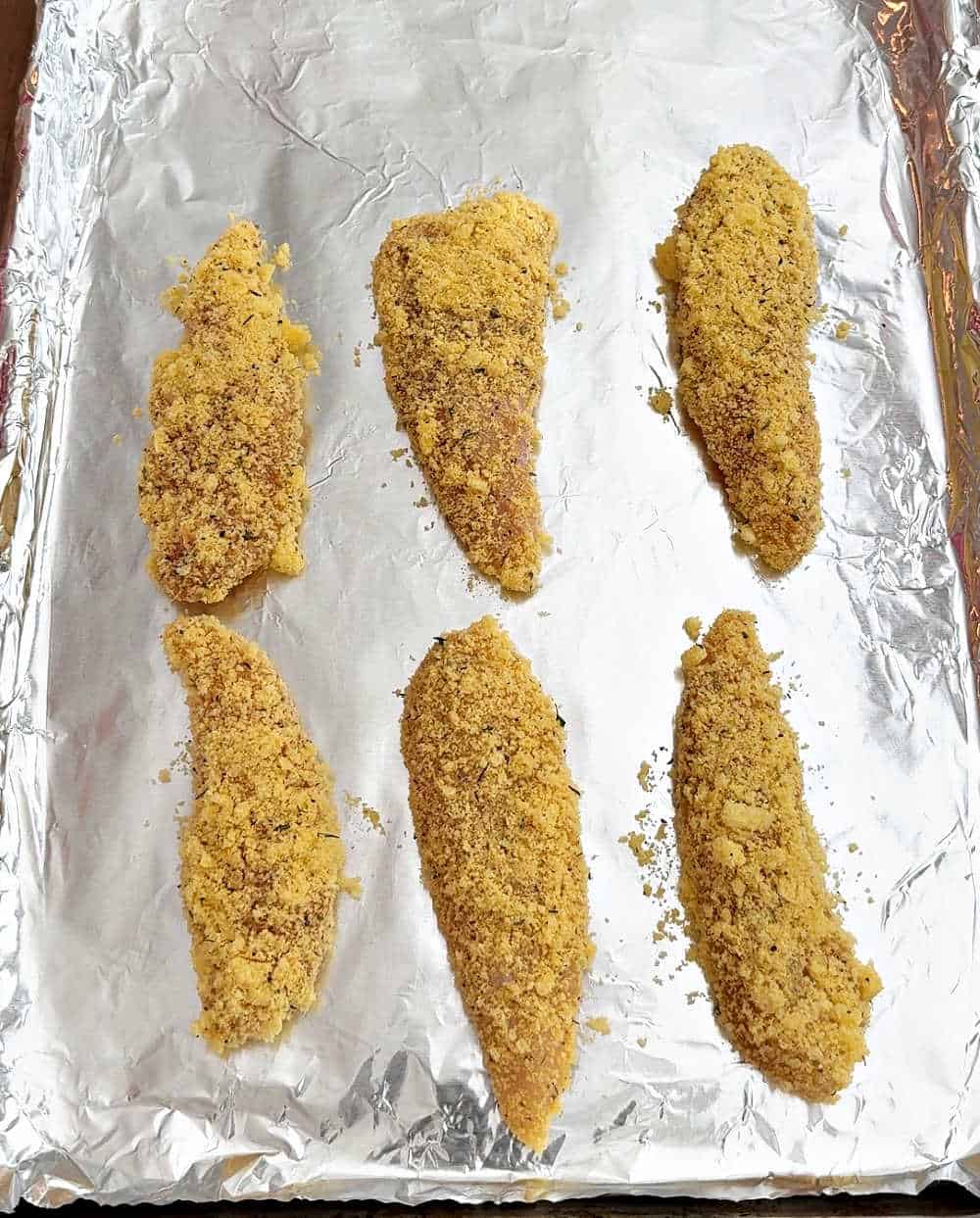 breaded chicken strips on baking sheet.