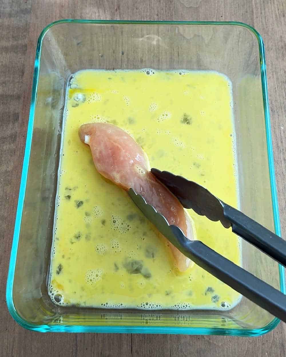 coating chicken in egg wash.