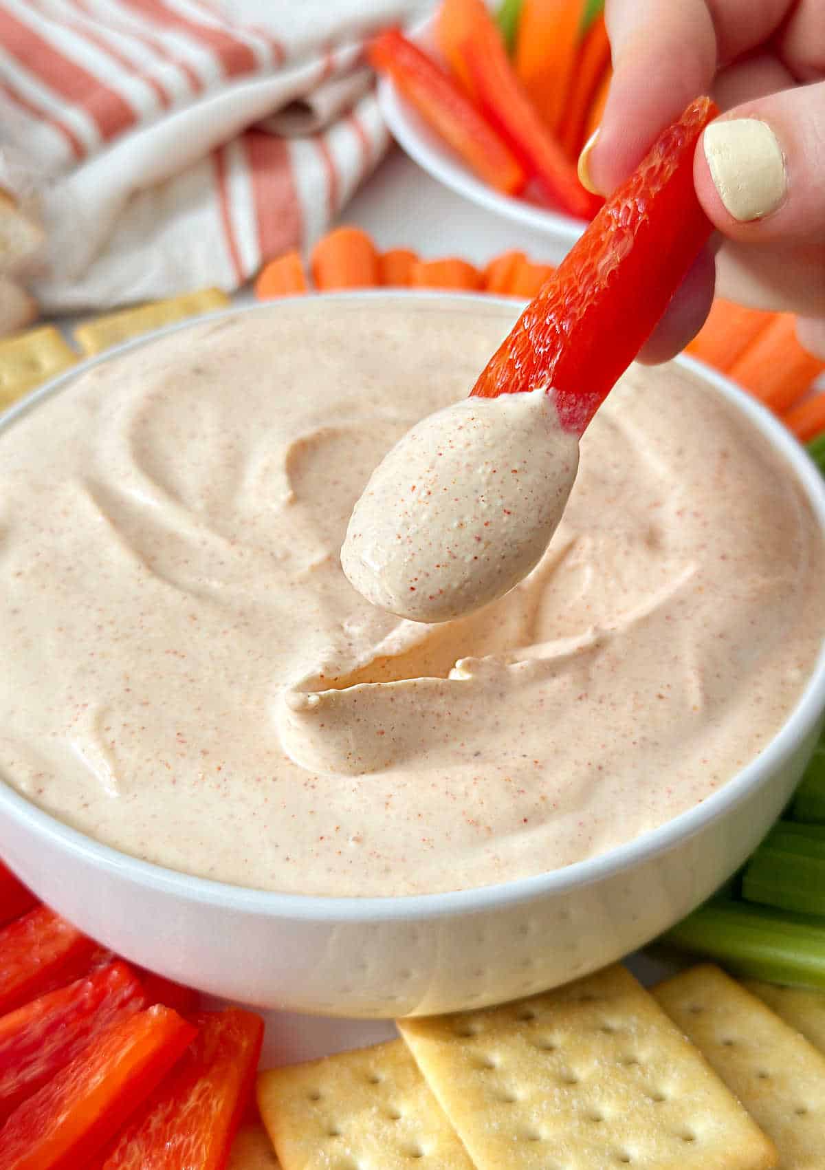 dipping sliced bell pepper into ghost pepper dip.