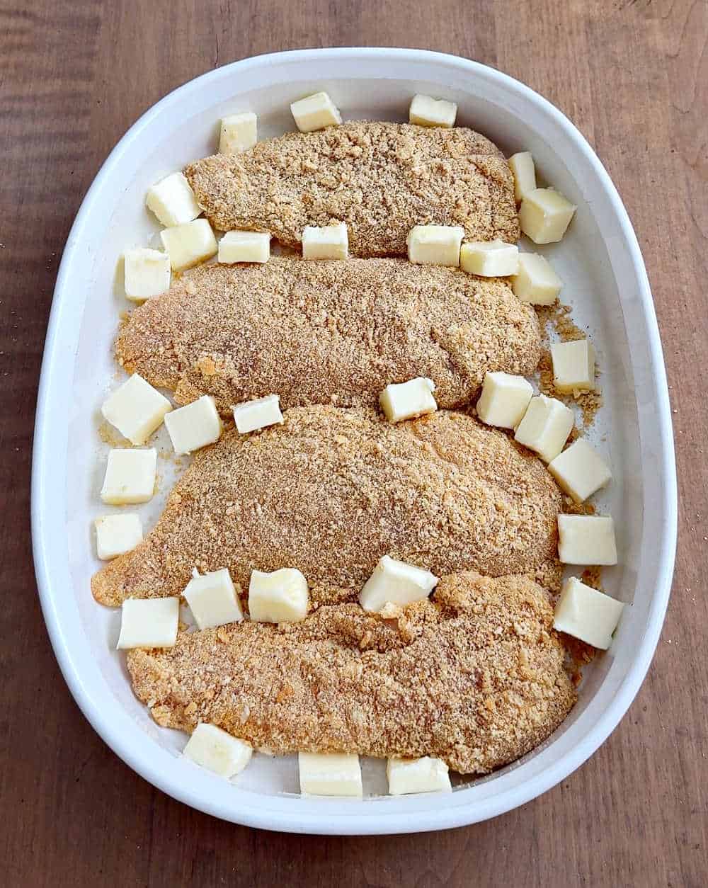 butter cubes with chicken in casserole dish.