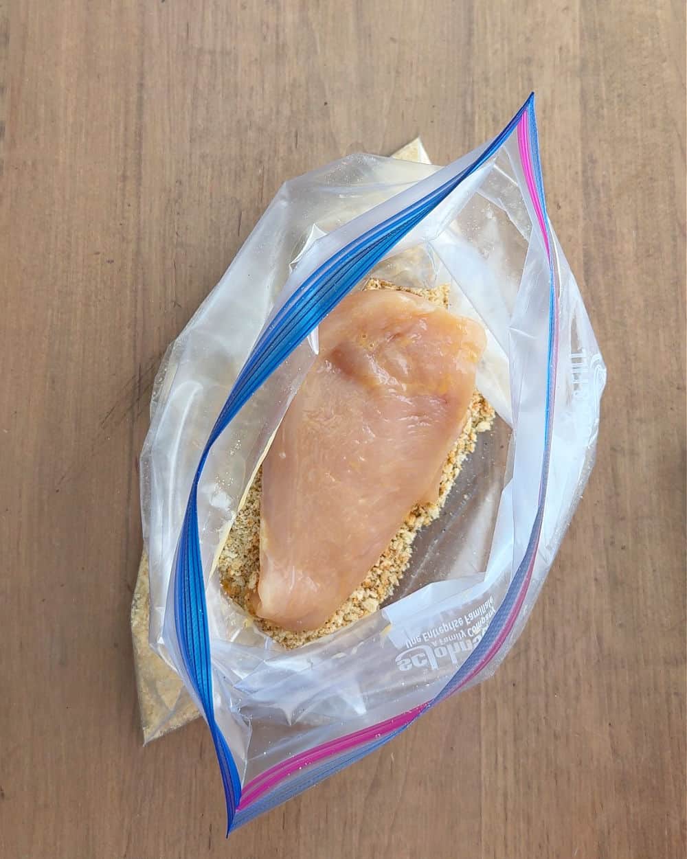 coating chicken with cracker crumbs in zip top bag.