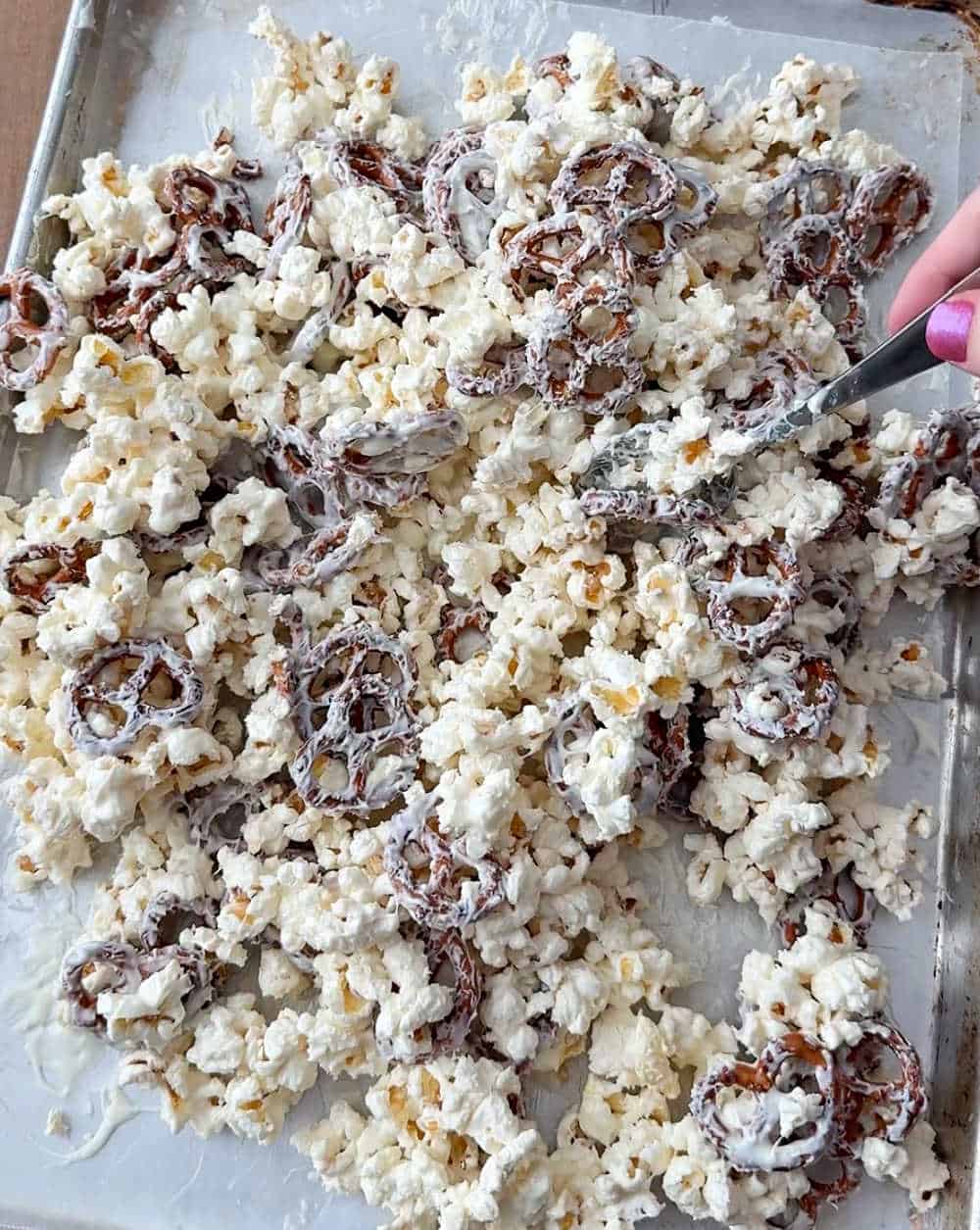stirring melted white chocolate with pretzels and popcorn.