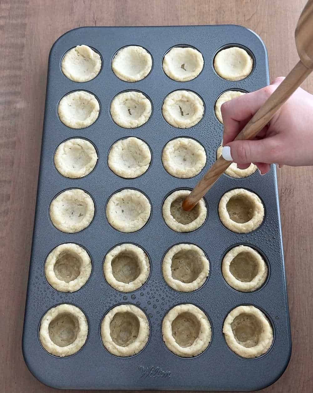 pressing wooden spoon handle into cookies.