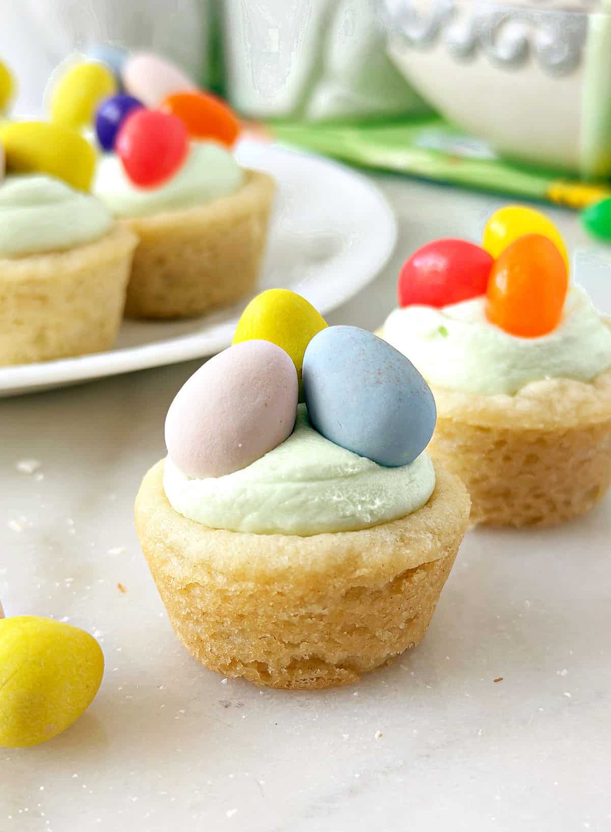 Easter basket cookie cups topped with candy eggs.