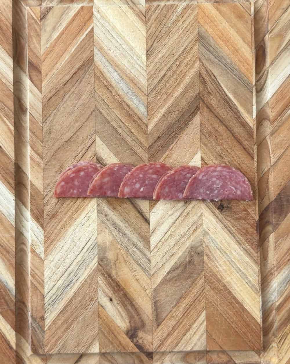 row of folded salami on cutting board.