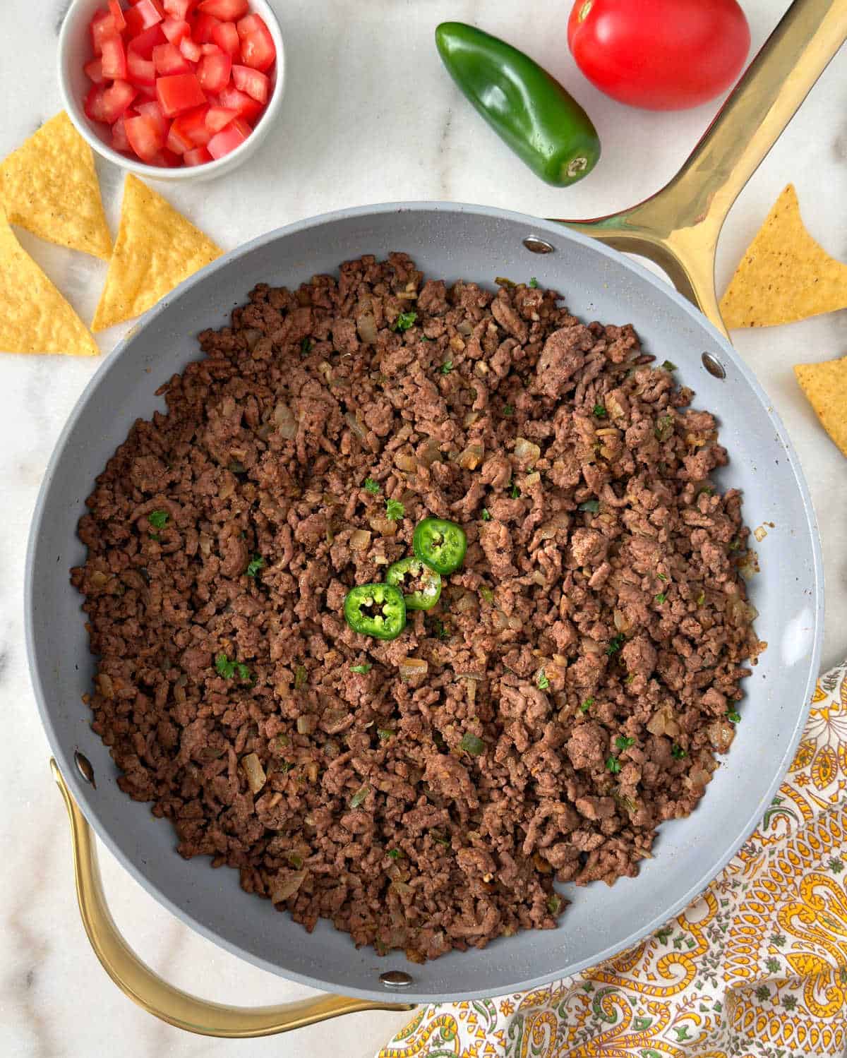 ground beef taco meat in skillet with jalapeno slices.