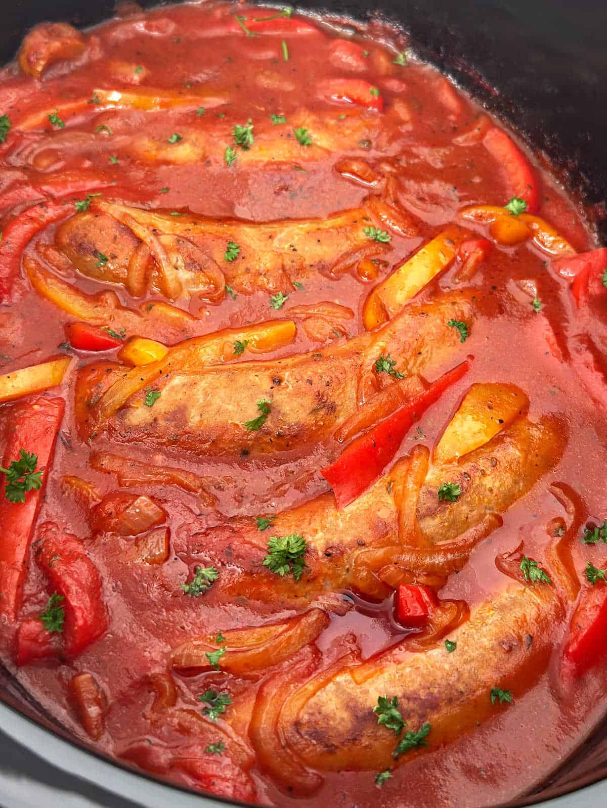 Italian sausage and peppers in tomato sauce in slow cooker.