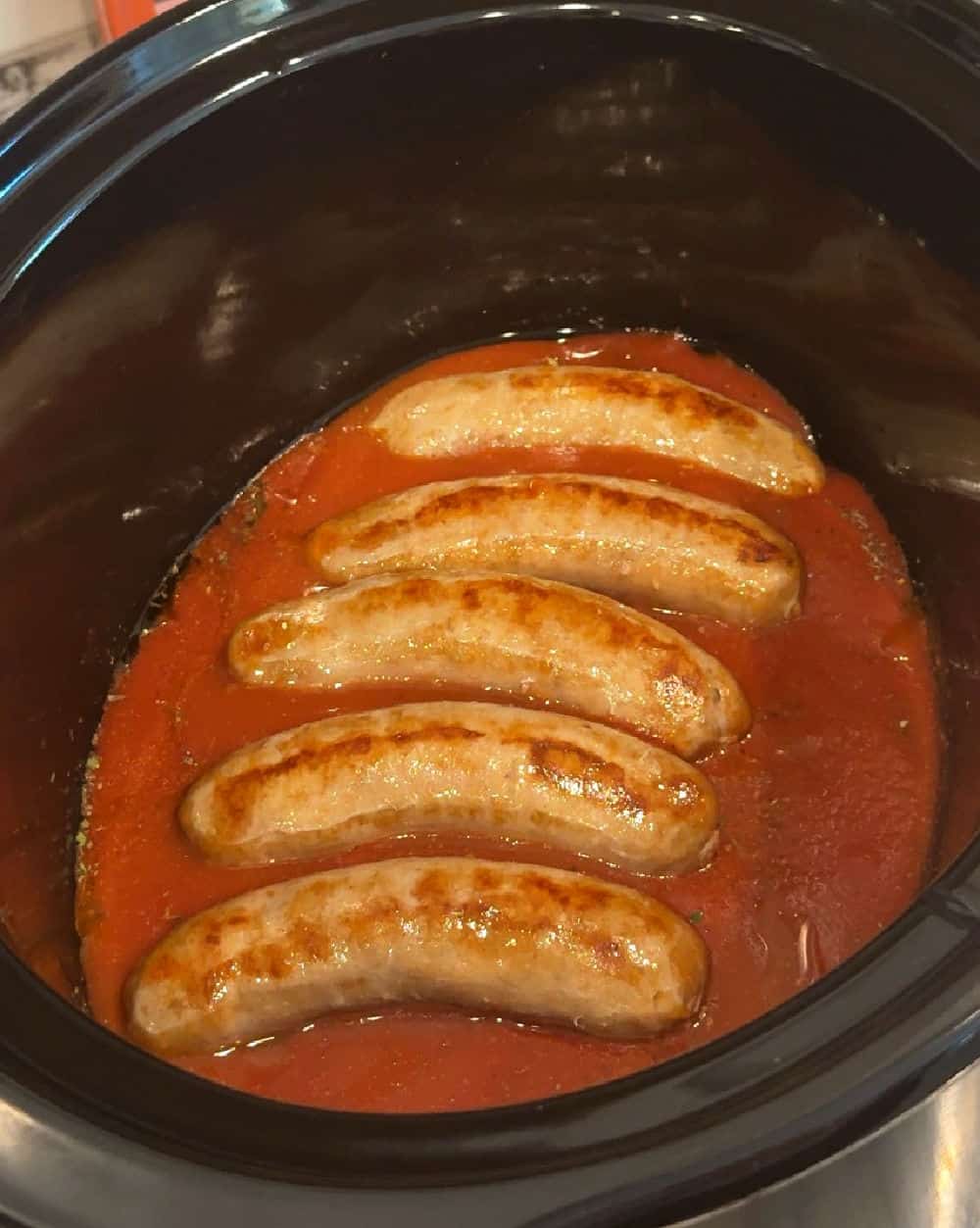 Italian sausages in tomato sauce in crock pot.