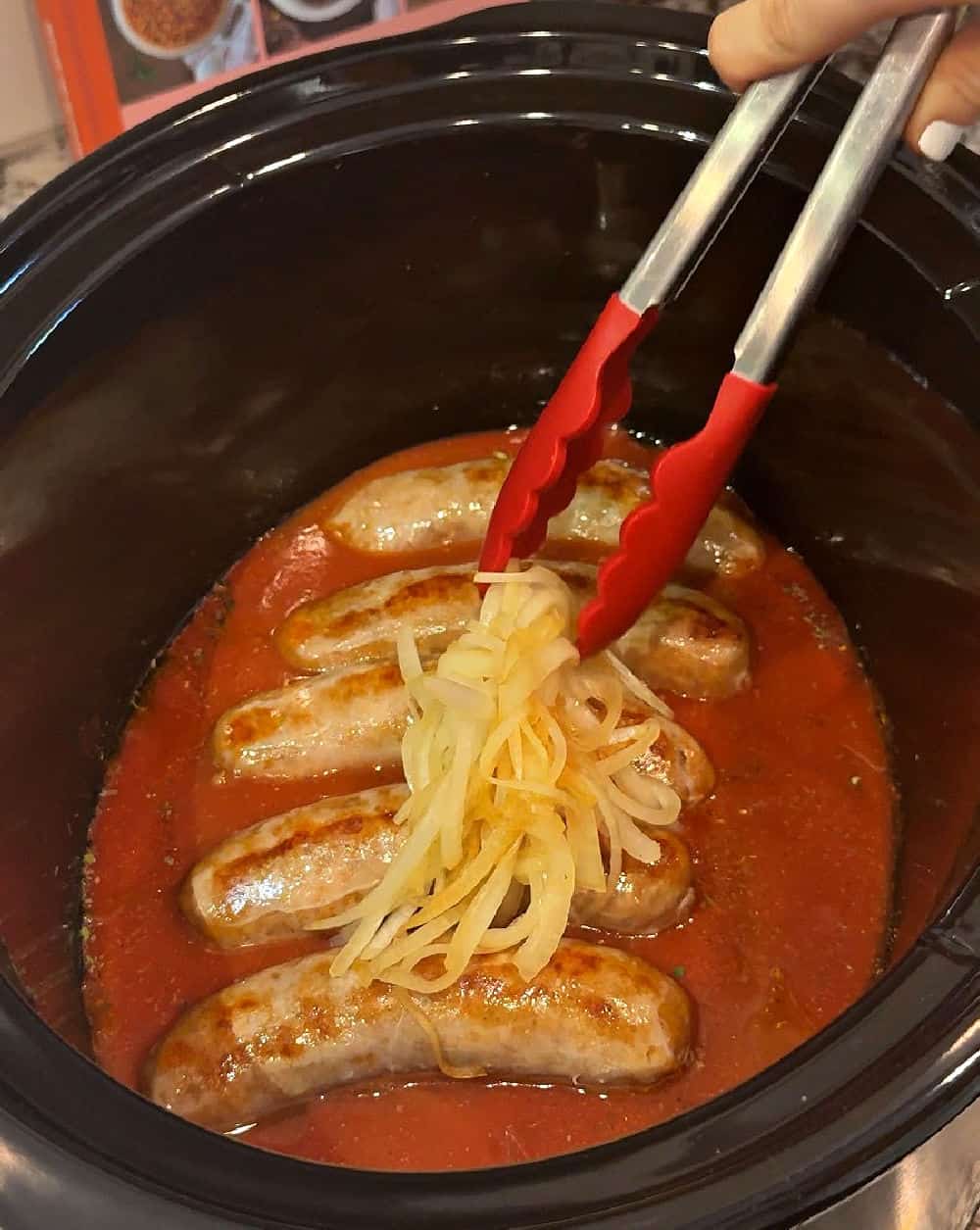 placing fried onions over sausages.