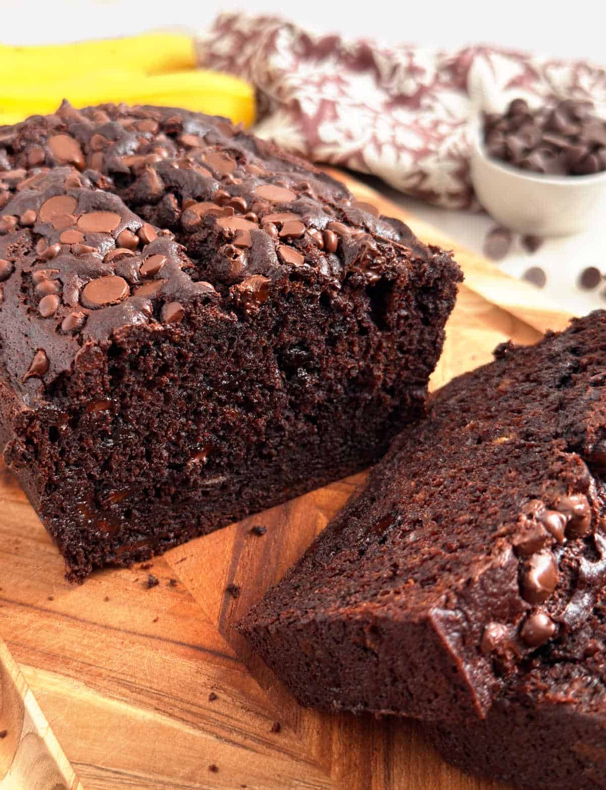 chocolate banana bread with chocolate chips on cutting board.