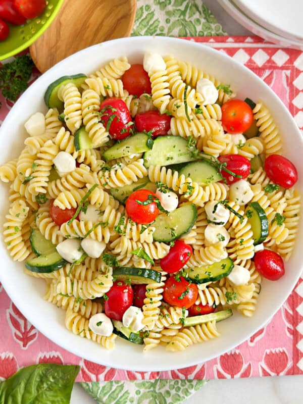 bowl of cucumber tomato pasta salad with mozzarella balls.