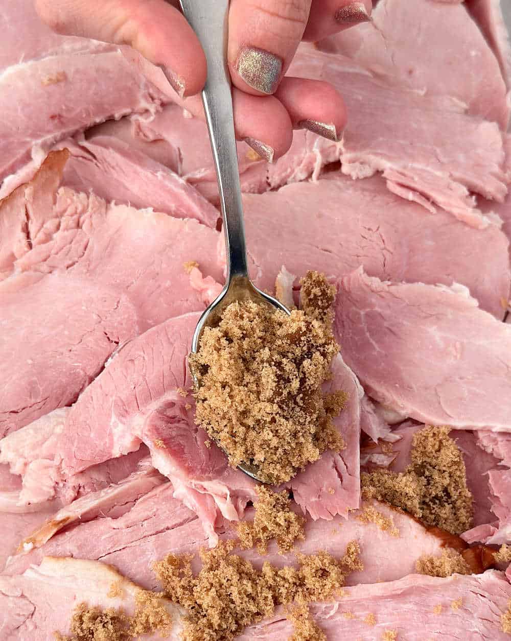 spooning brown sugar honey mixture over ham.