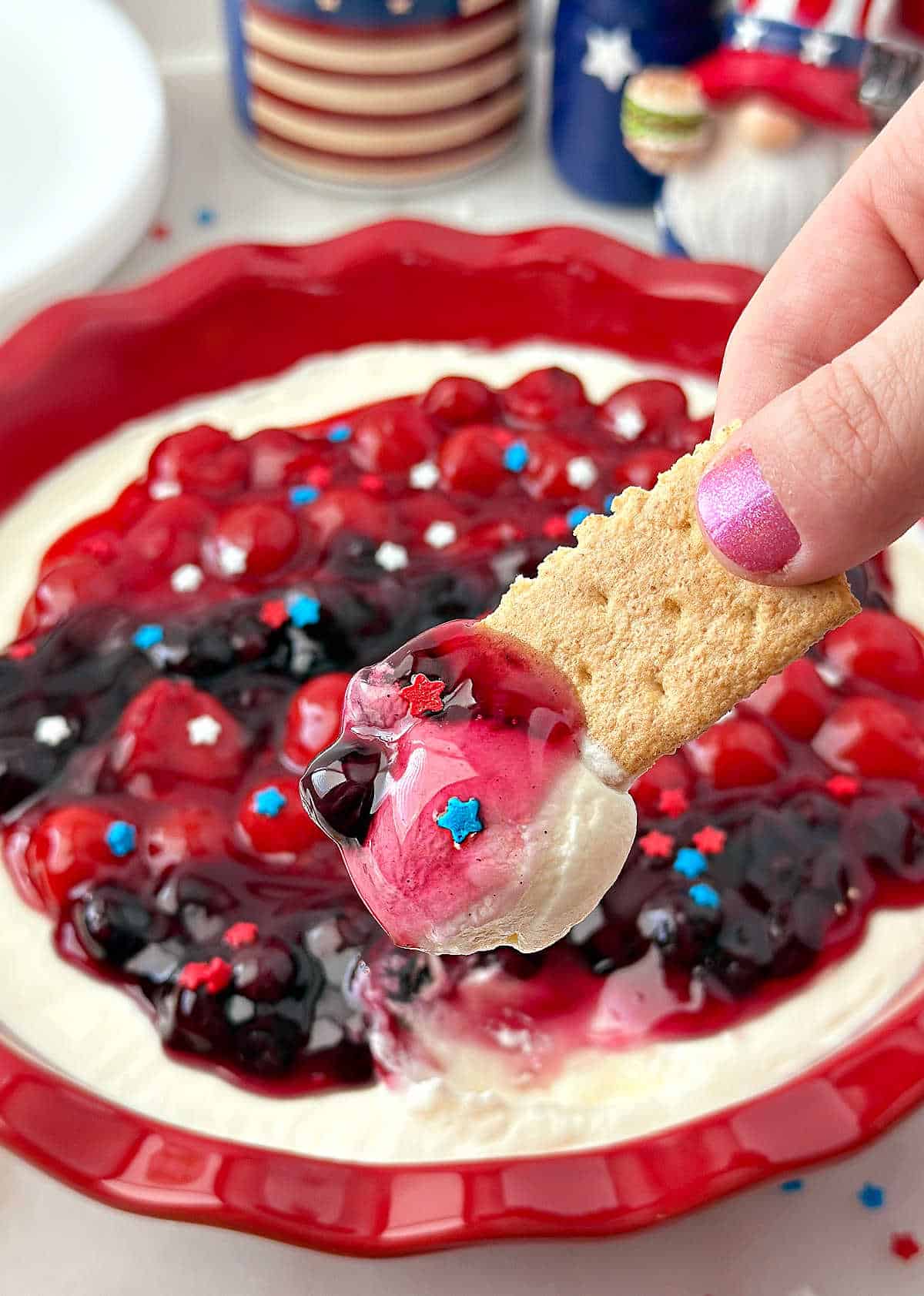 red, white and blue cheesecake dip on graham cracker.