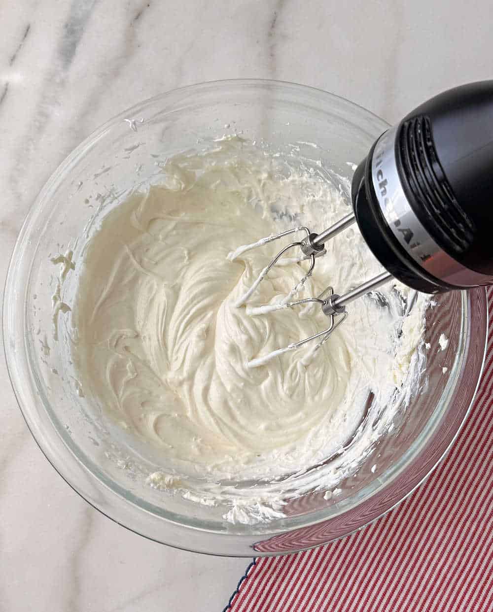 mixing cheesecake filling in glass bowl.