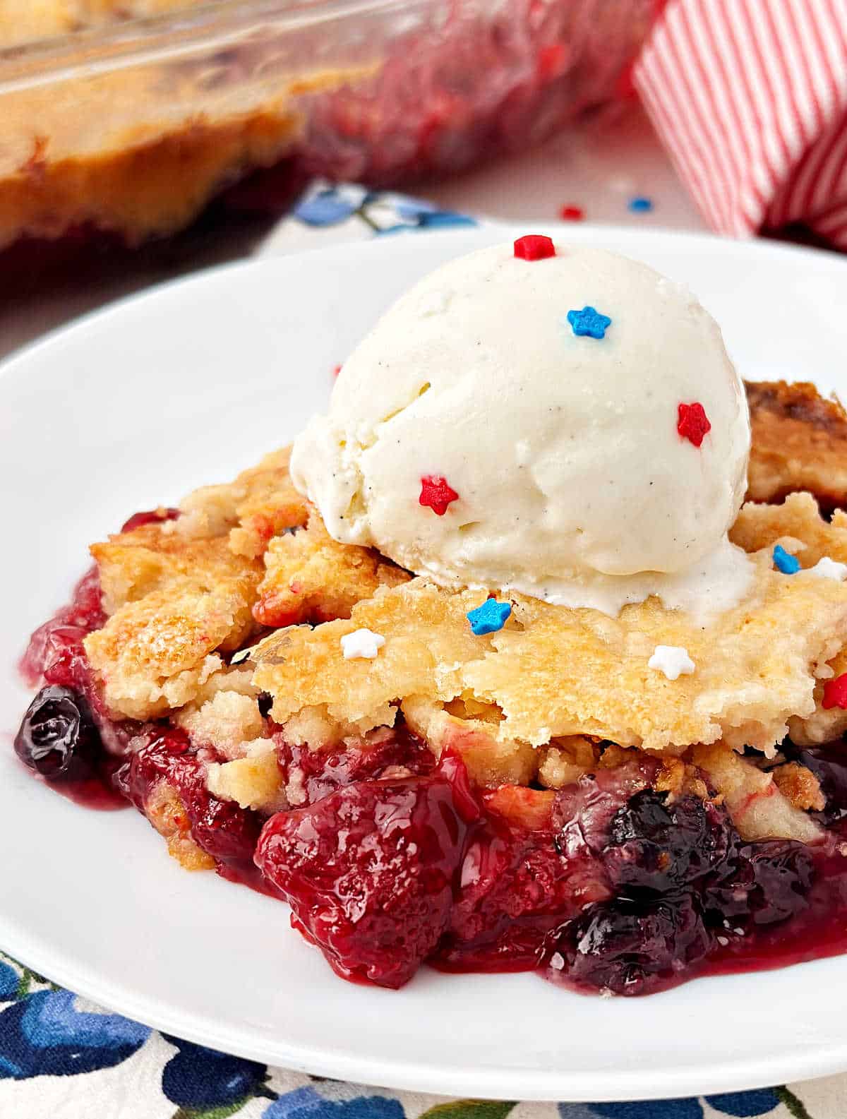 red white and blue dump cake with strawberries, blueberries and vanilla ice cream.
