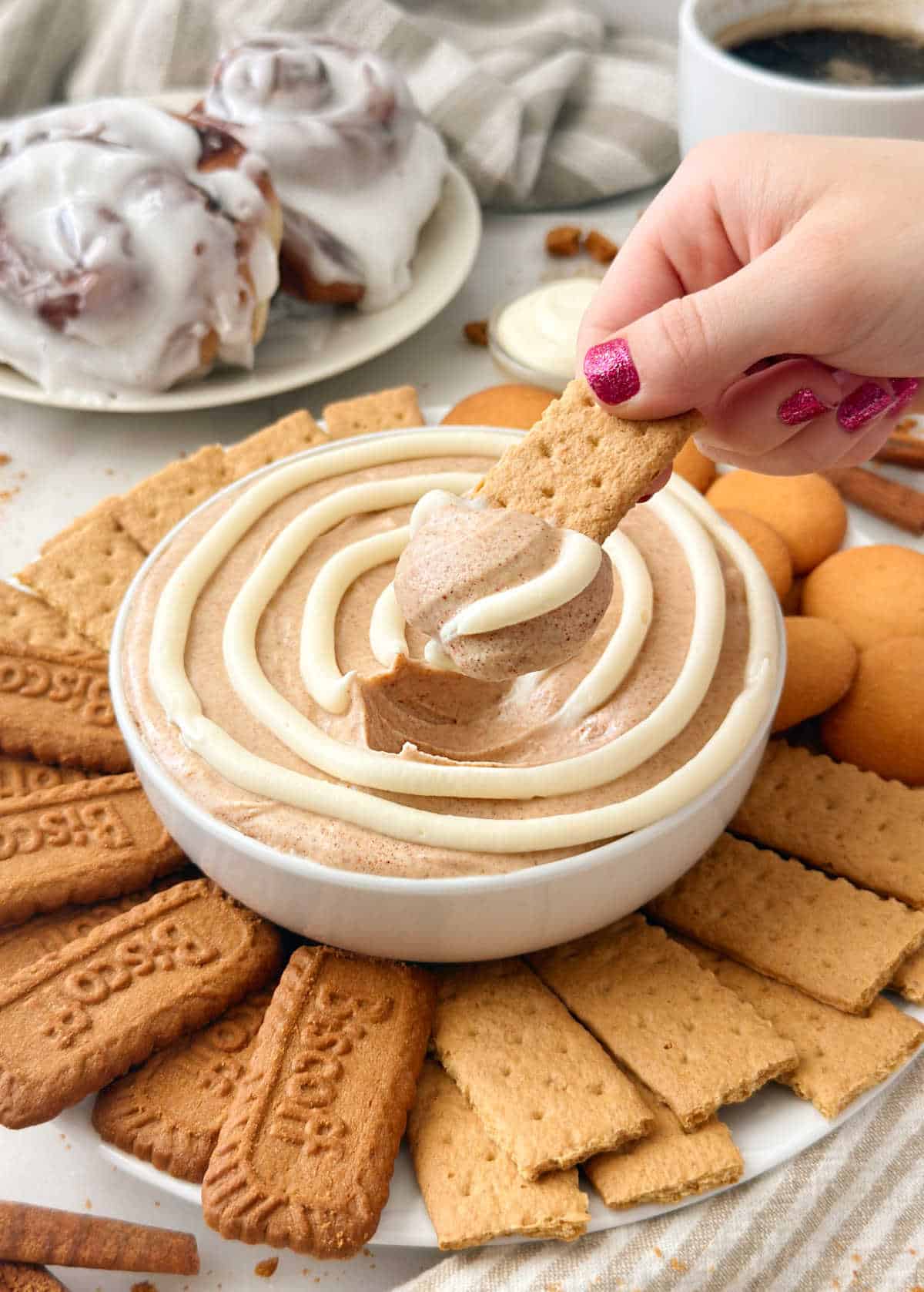 dipping graham cracker into cinnamon roll dip.