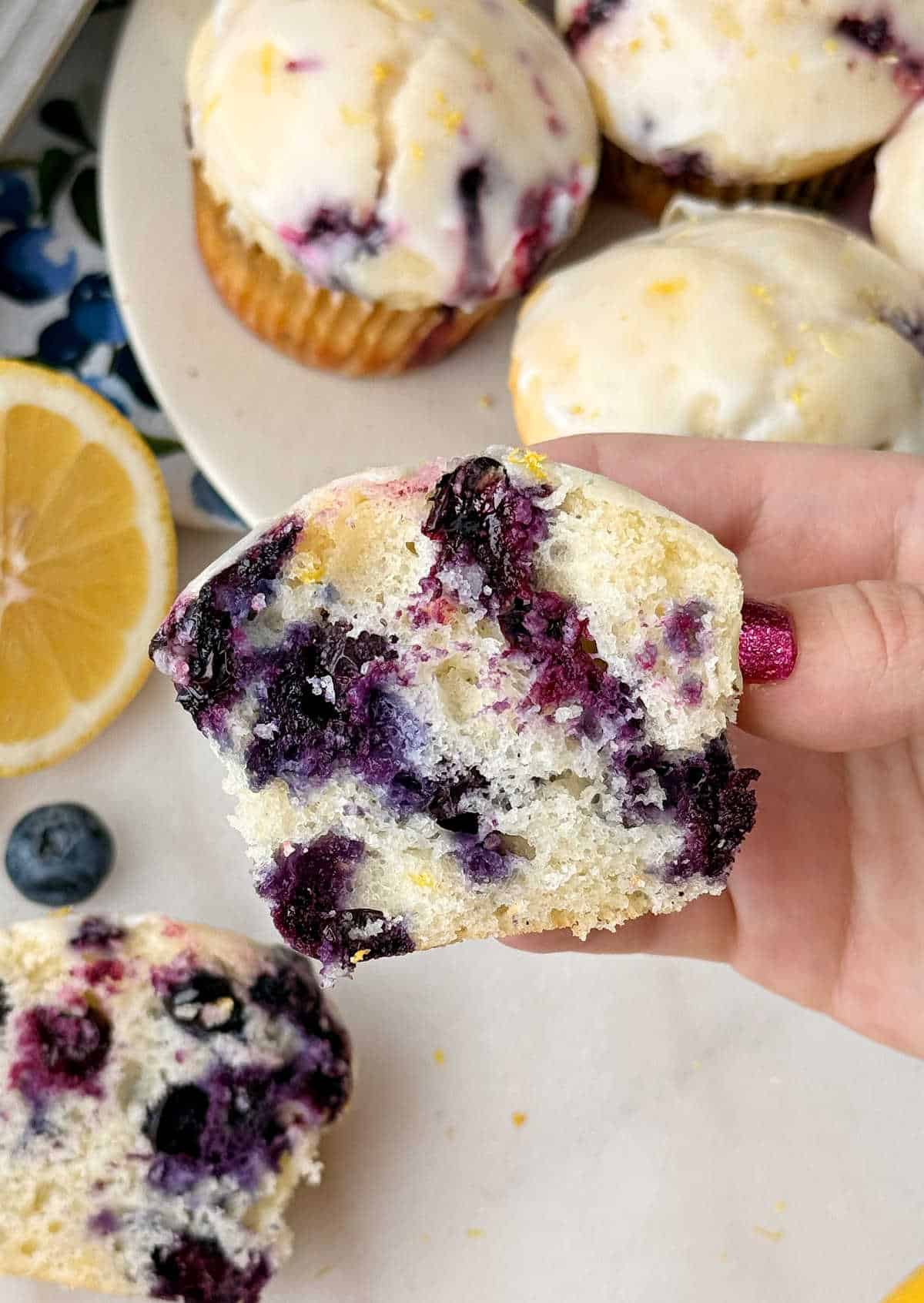hand holding lemon blueberry muffin cut in half.