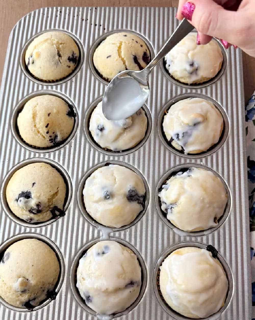 spooning glaze on top of muffins.