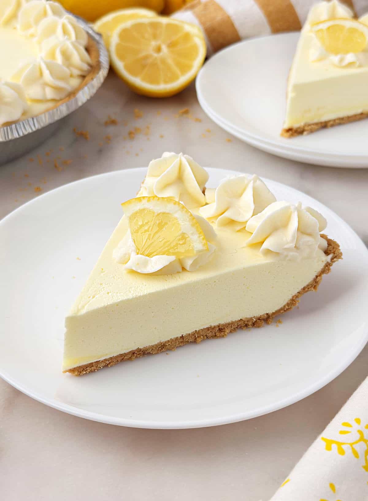 slices of lemon jello pie on white plates with piped whipped cream.
