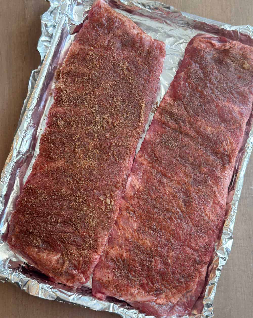 spice rubbed ribs on foil lined baking sheet.