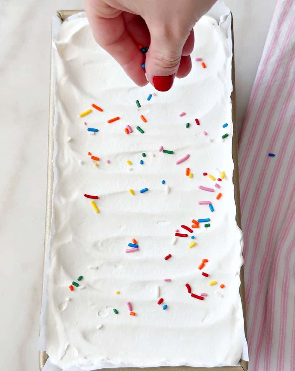 adding sprinkles on top of cake.