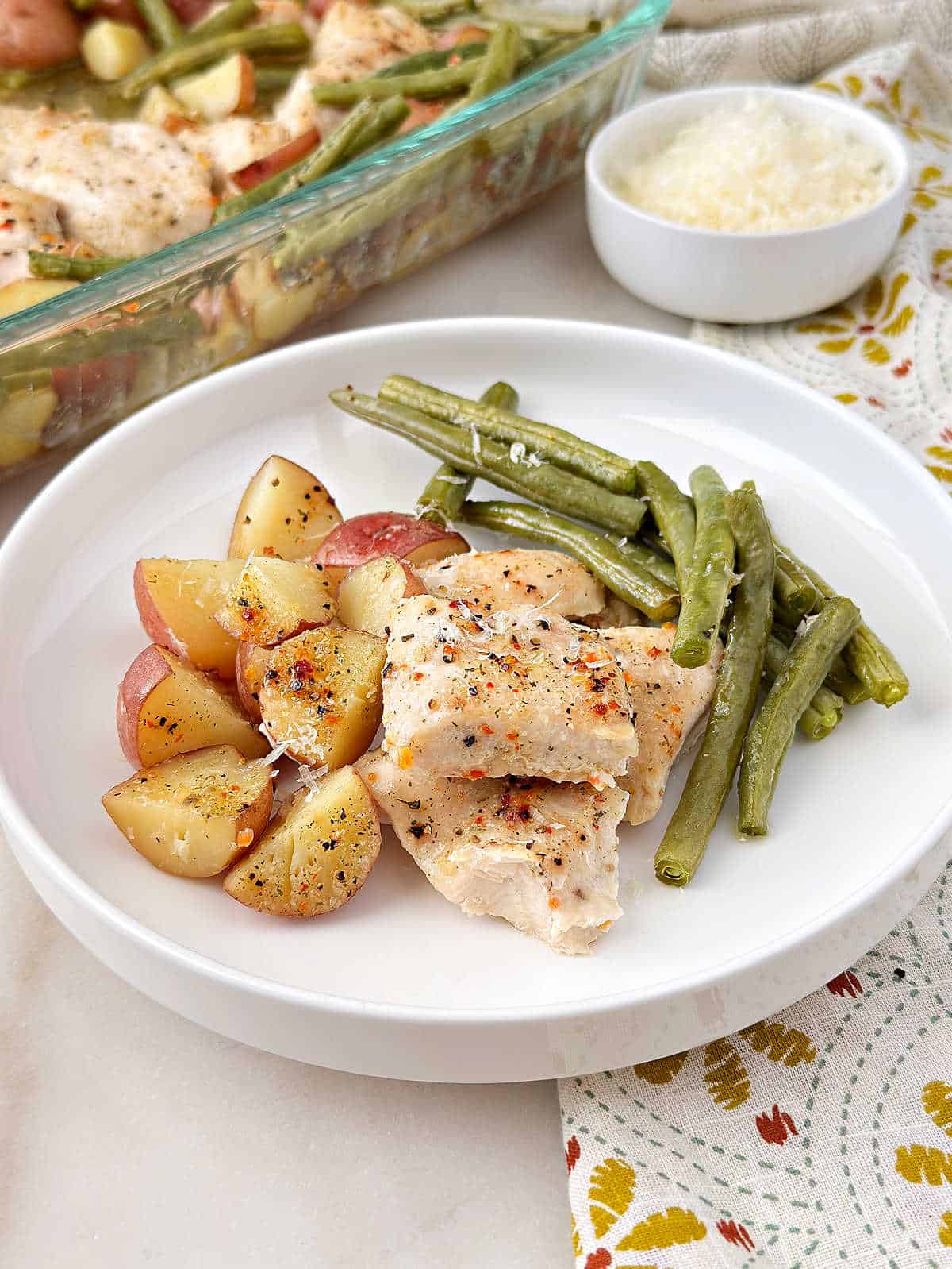 Italian chicken, green beans and red potatoes on a white dish.