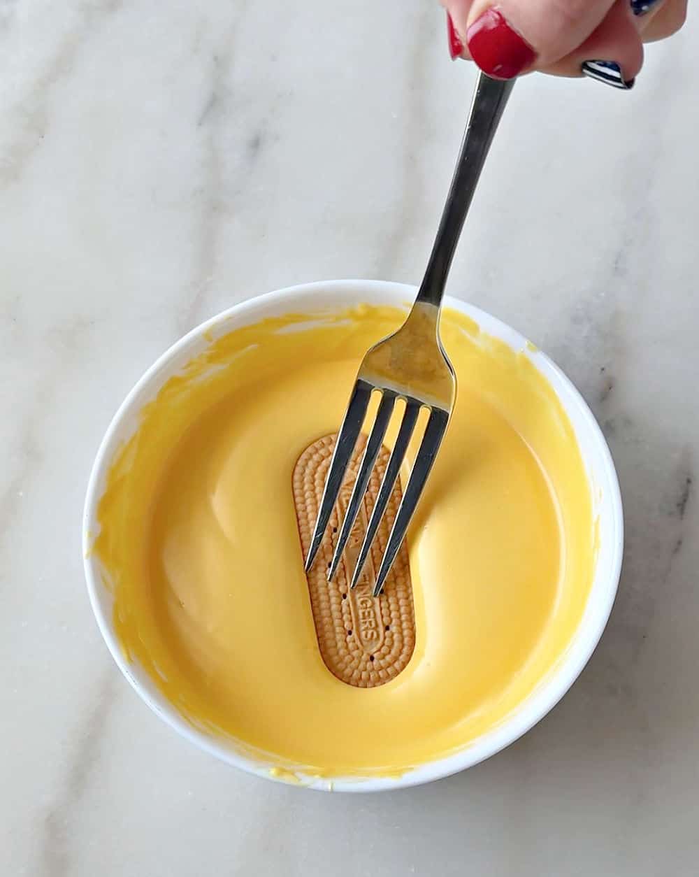 dipping cookie in melted yellow coating.