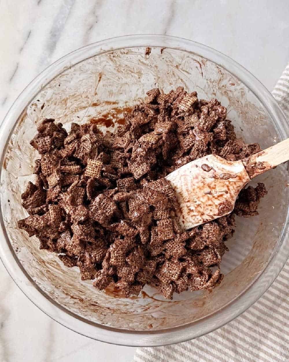 mixing chex cereal into chocolate with spatula.