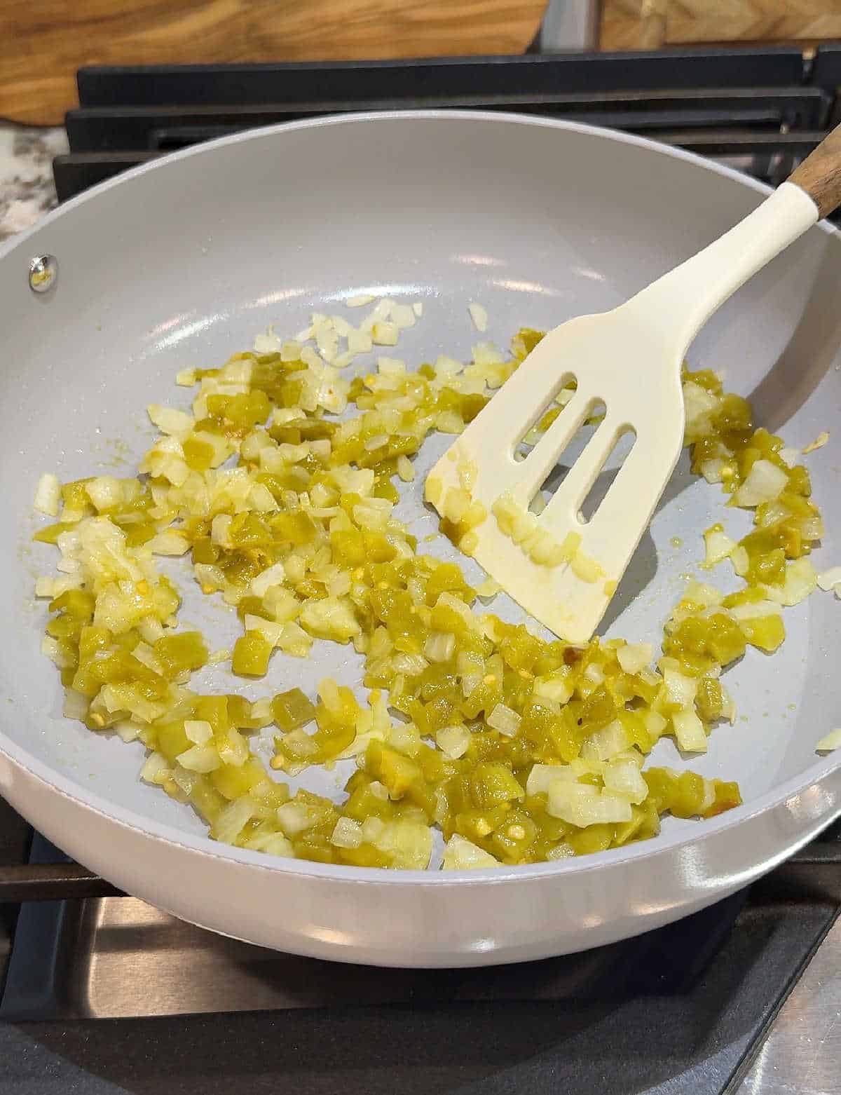 cooking onion and green chiles in pan.
