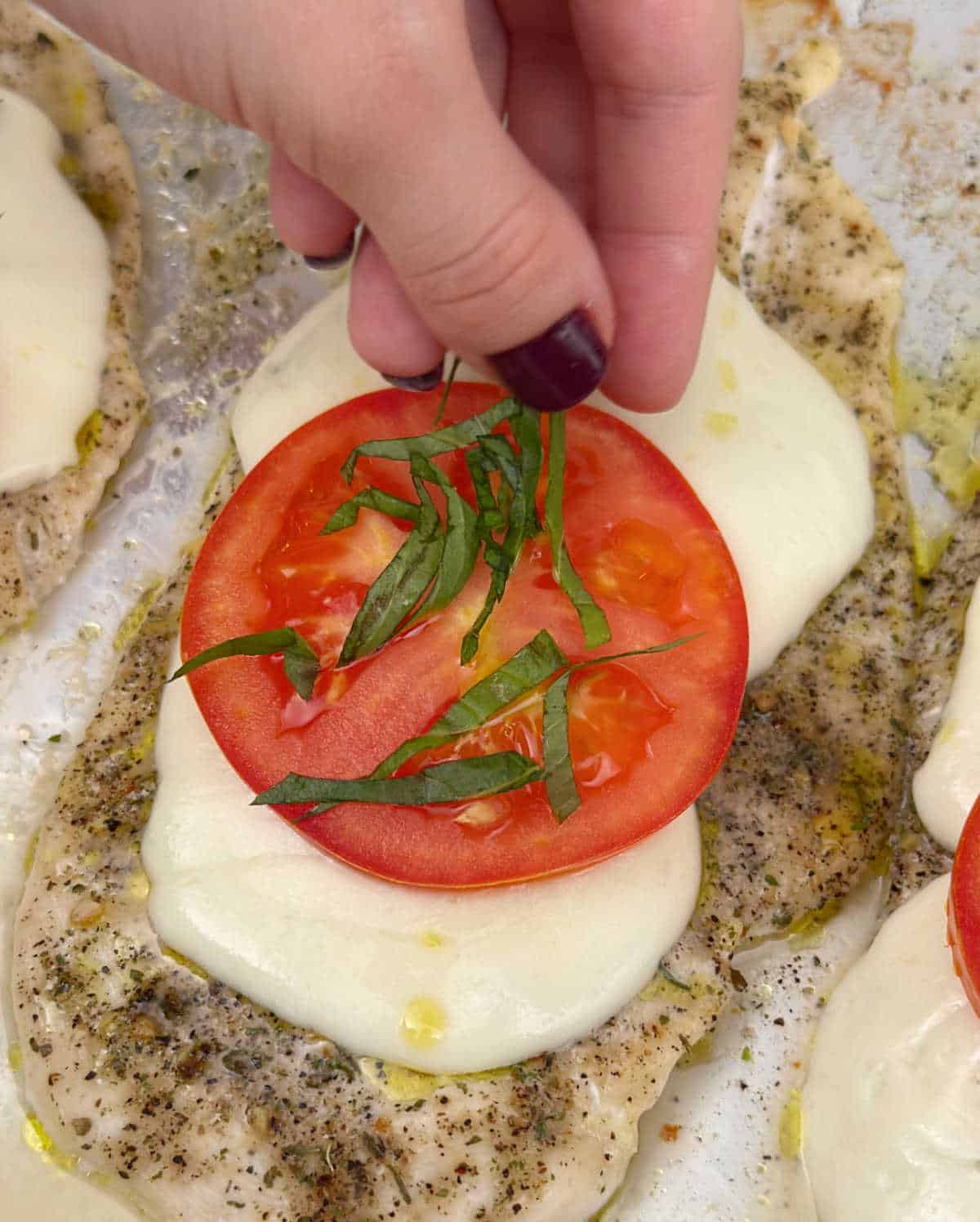 adding basil chiffonade over tomato.