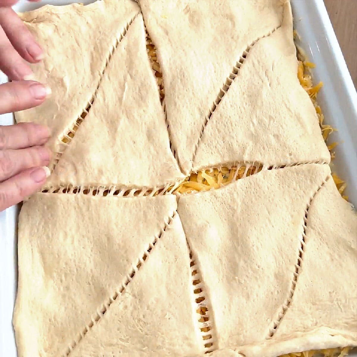 adding crescent roll dough on top of casserole.