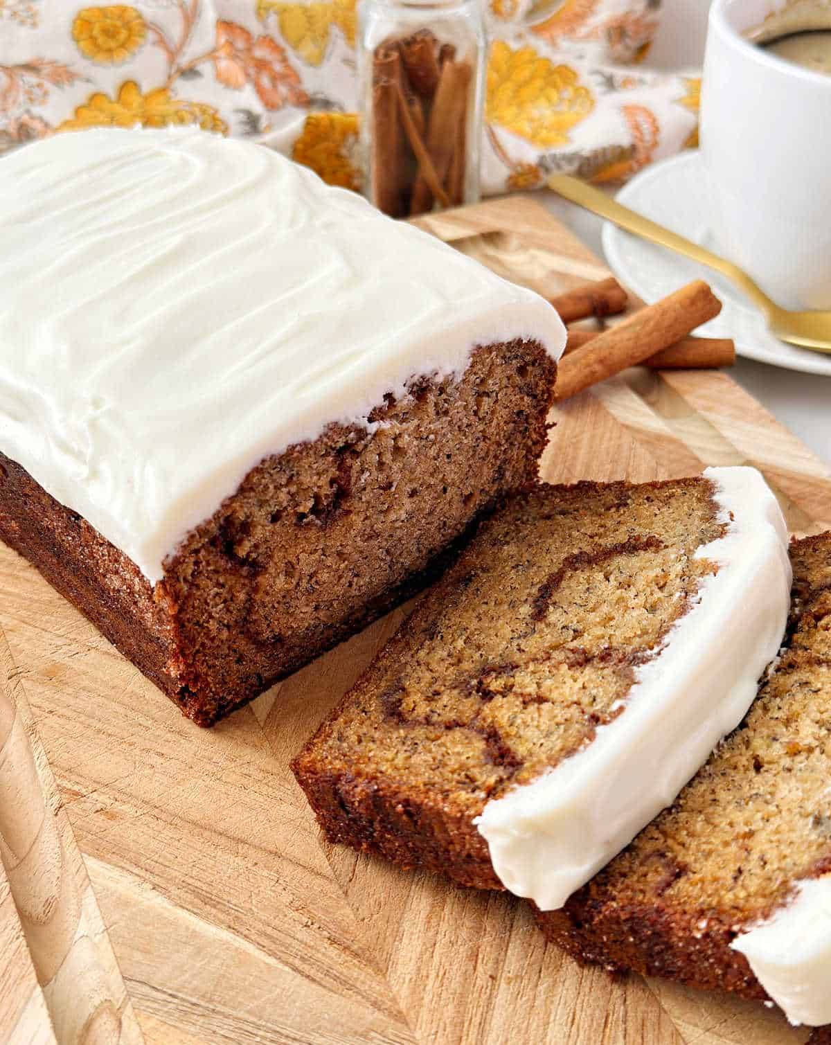 cinnamon roll banana bread with sweet cream cheese frosting on cutting board.