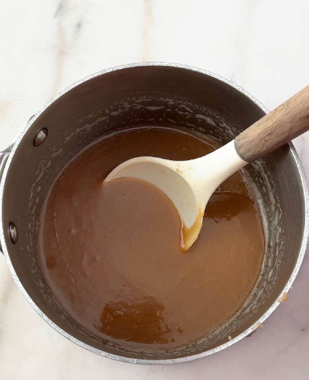 stirring caramel sauce in saucepan.