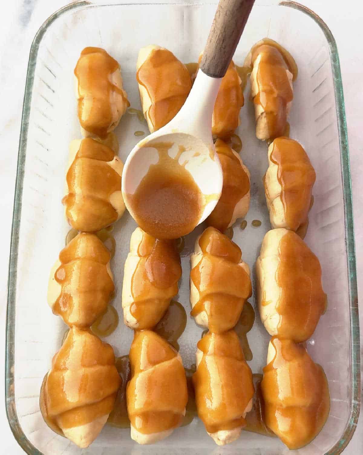 spooning caramel sauce over dumplings.