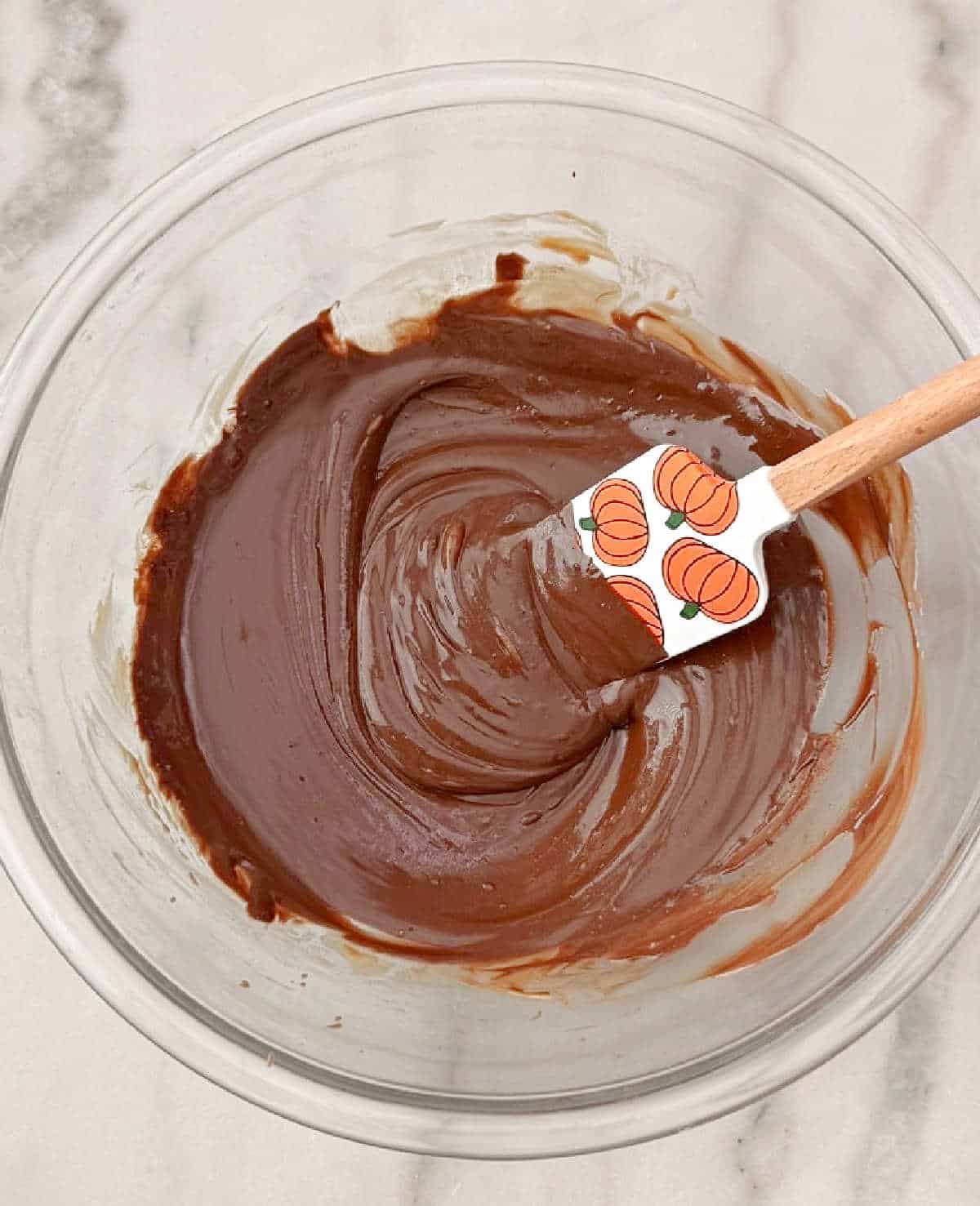 stirring melted chocolate mixture with pumpkin spatula.