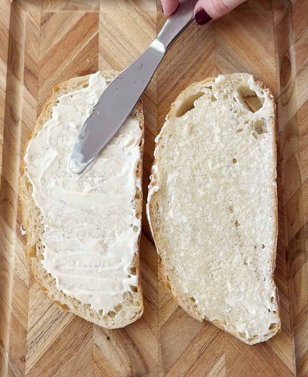 spreading mayonnaise on sourdough bread.