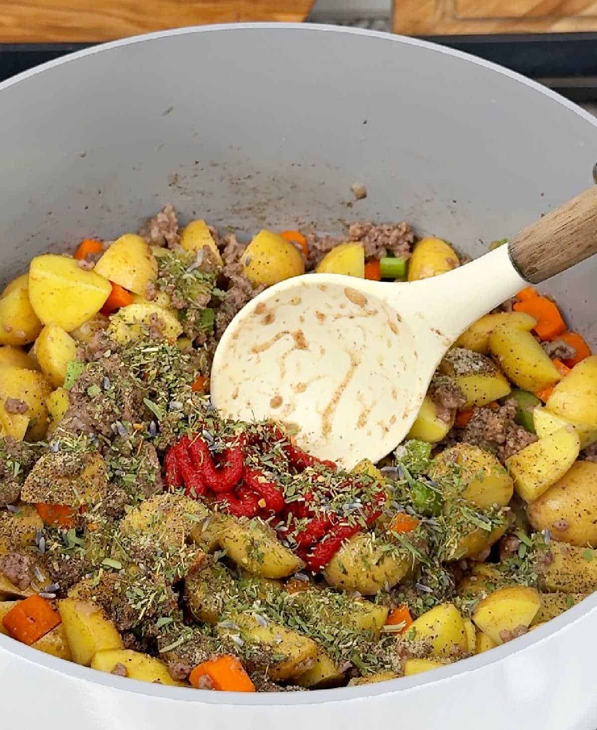 adding vegetables, tomato paste and seasonings.