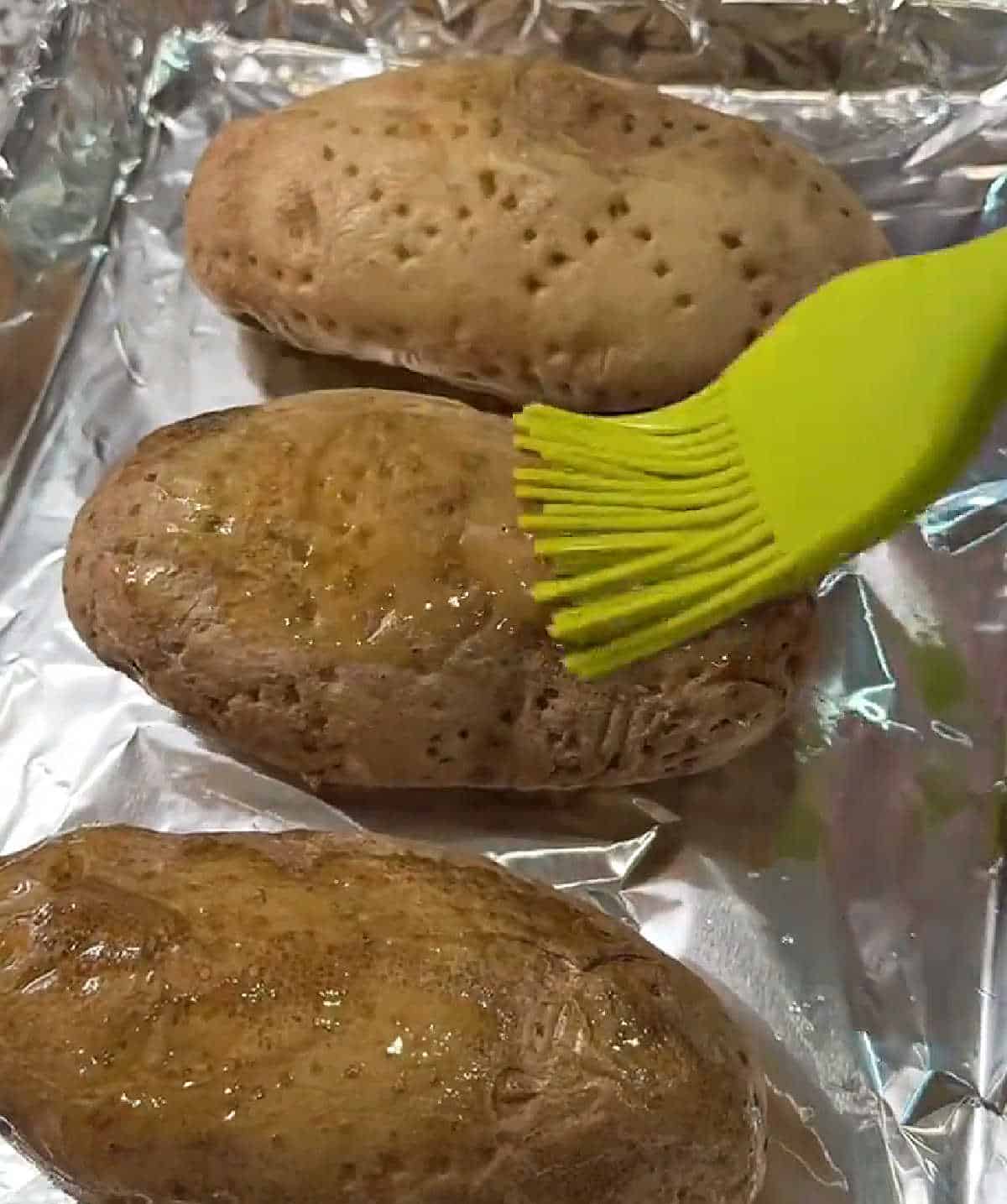 brushing baked potatoes with olive oil.