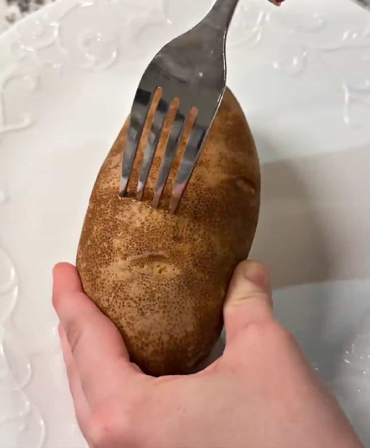 poking holes in potato with fork.