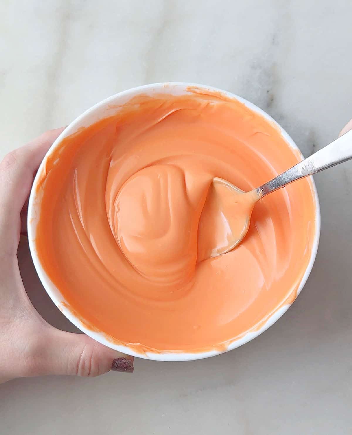 stirring melted orange candy coating.
