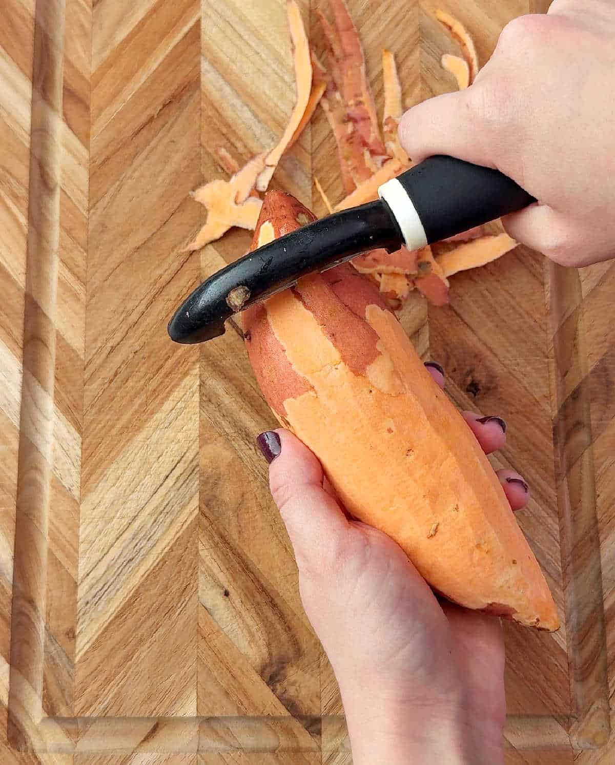 peeling a sweet potato with peeler.