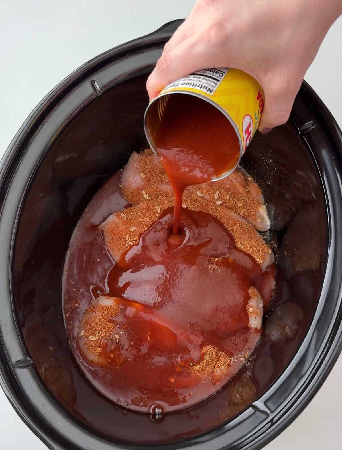 pouring red sauce over chicken.