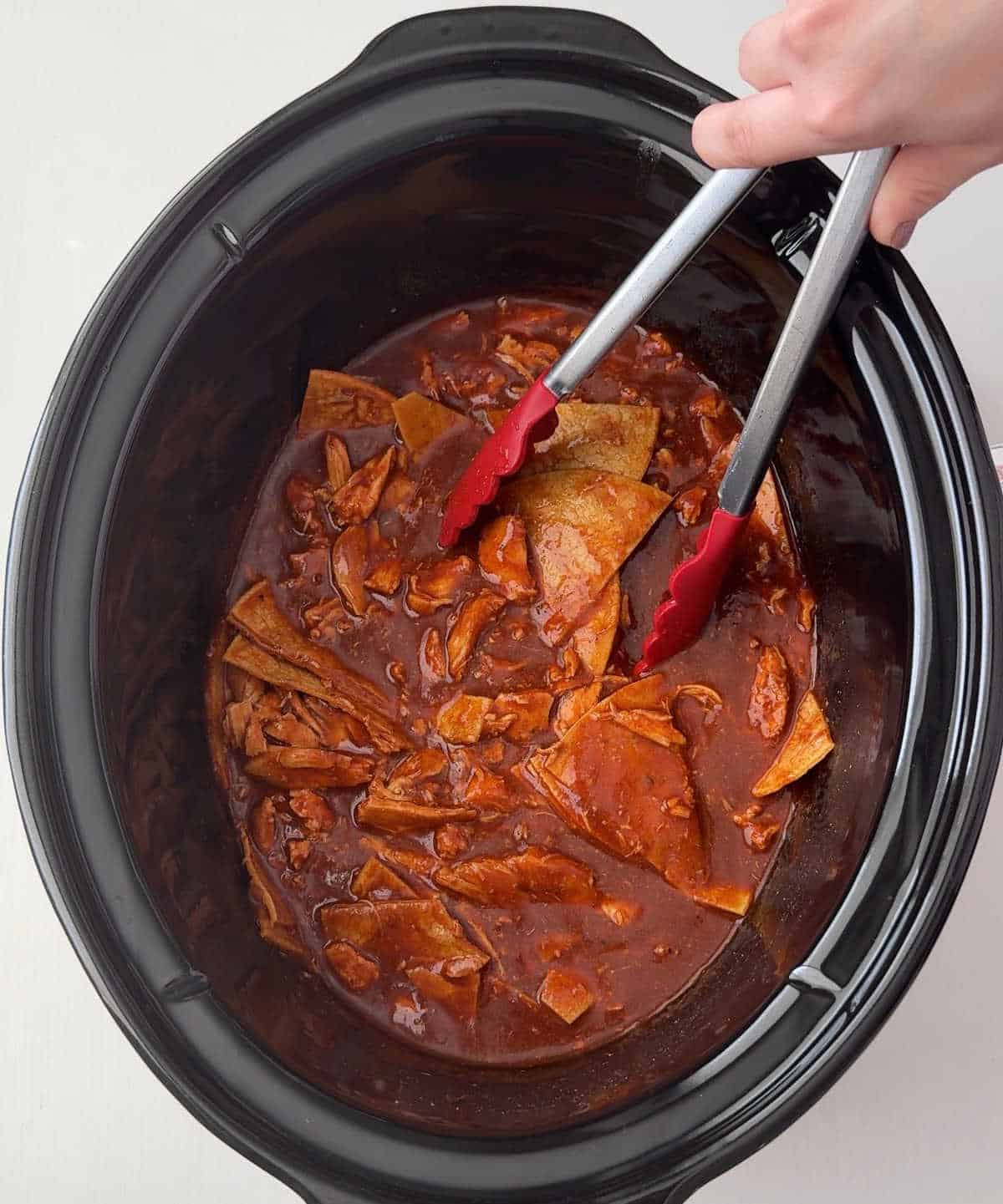 Adding tortillas to shredded chicken.
