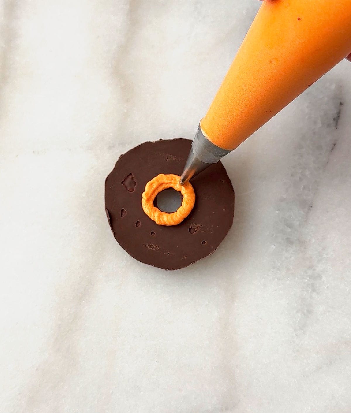 piping orange icing in center of cookie.