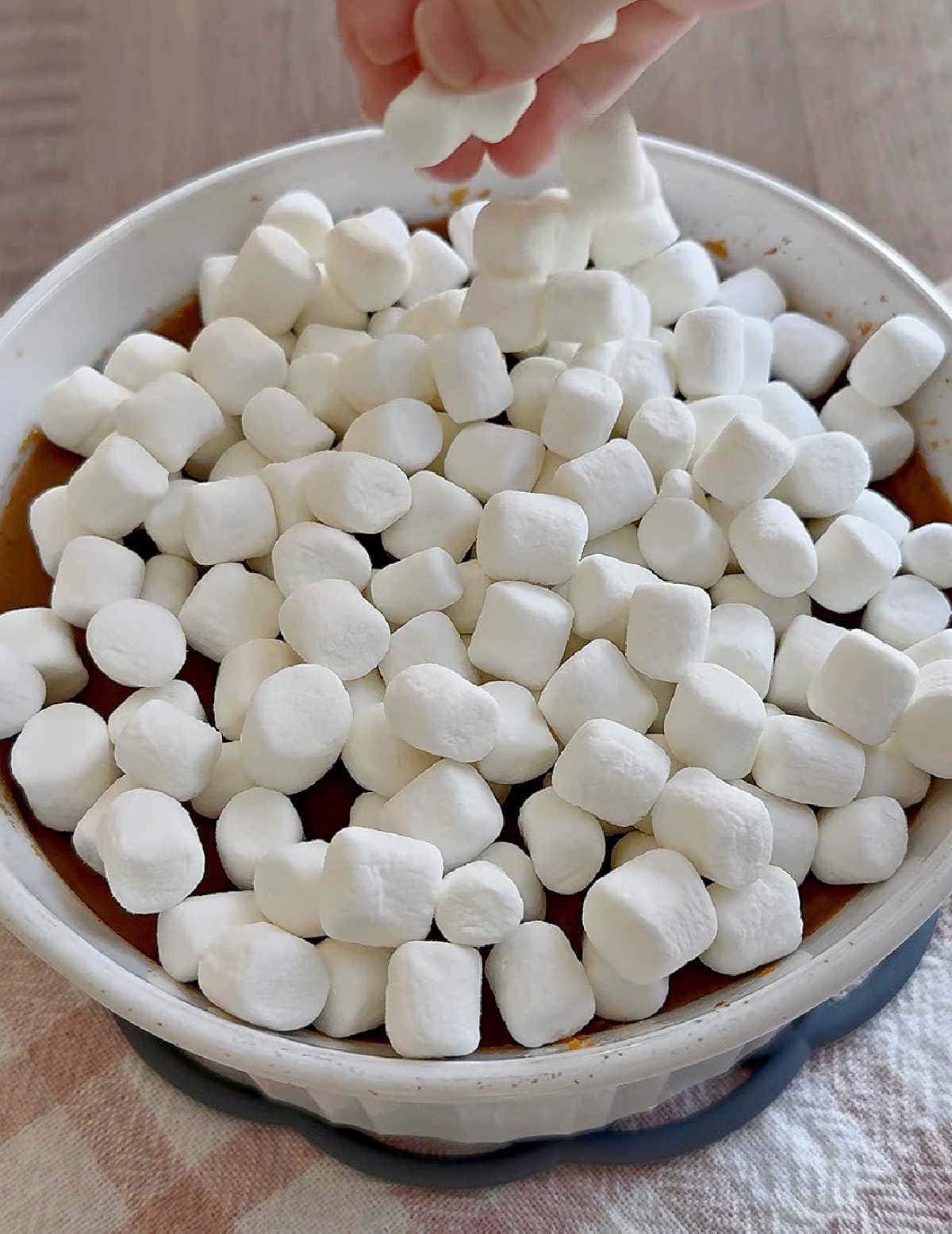 adding mini marshmallows on top of casserole.