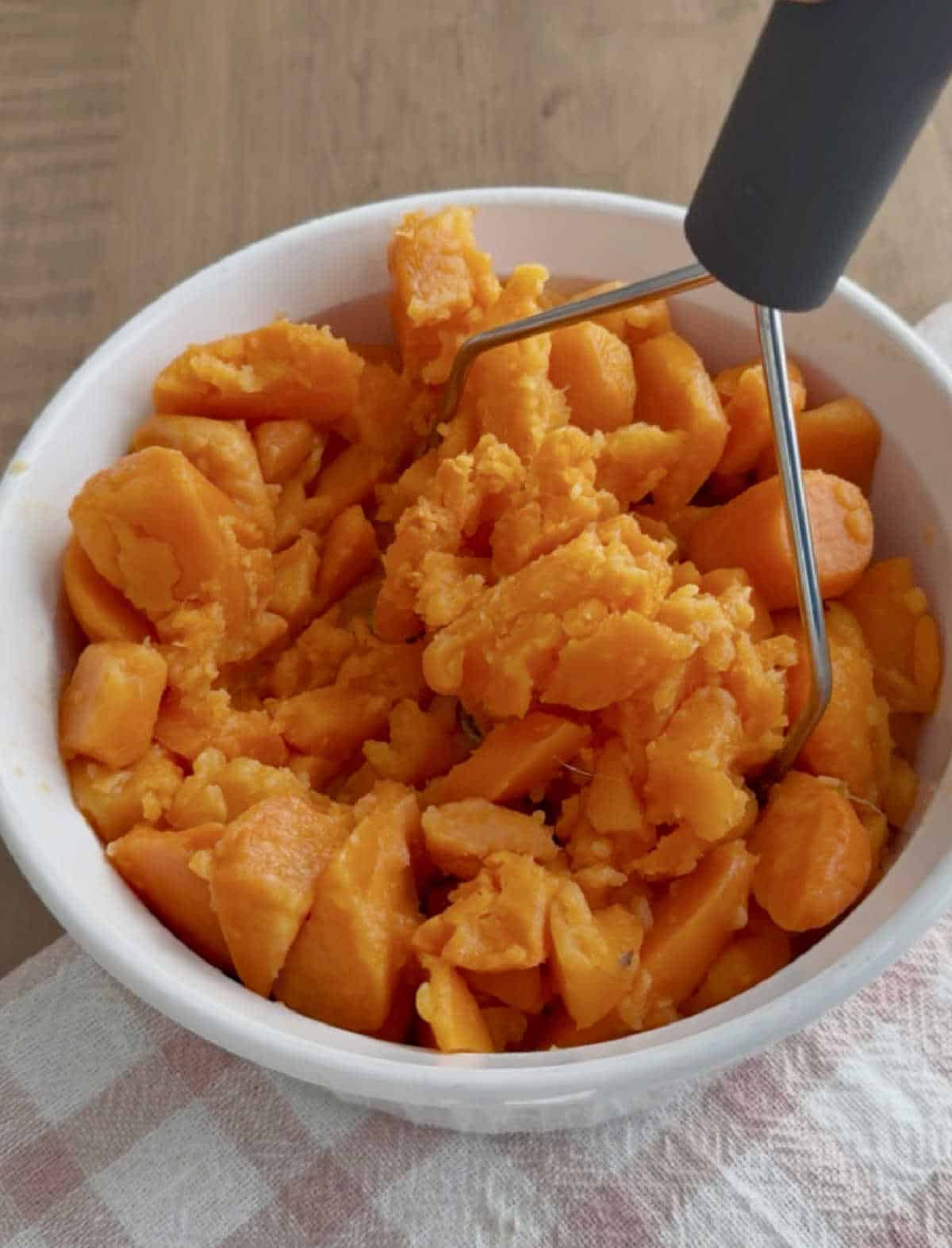 mashing canned yams with potato masher.