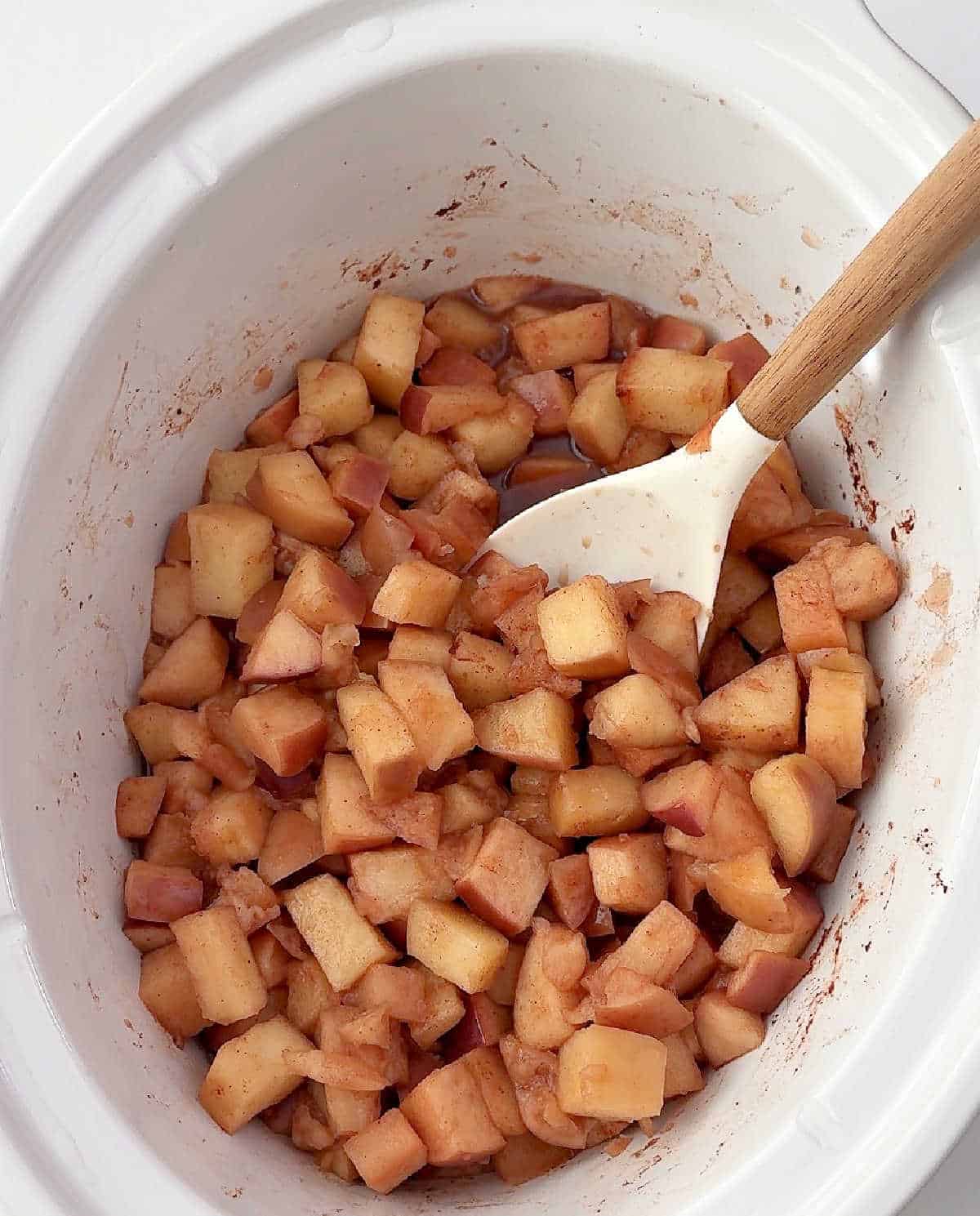 stirring cooked apples in crockpot.