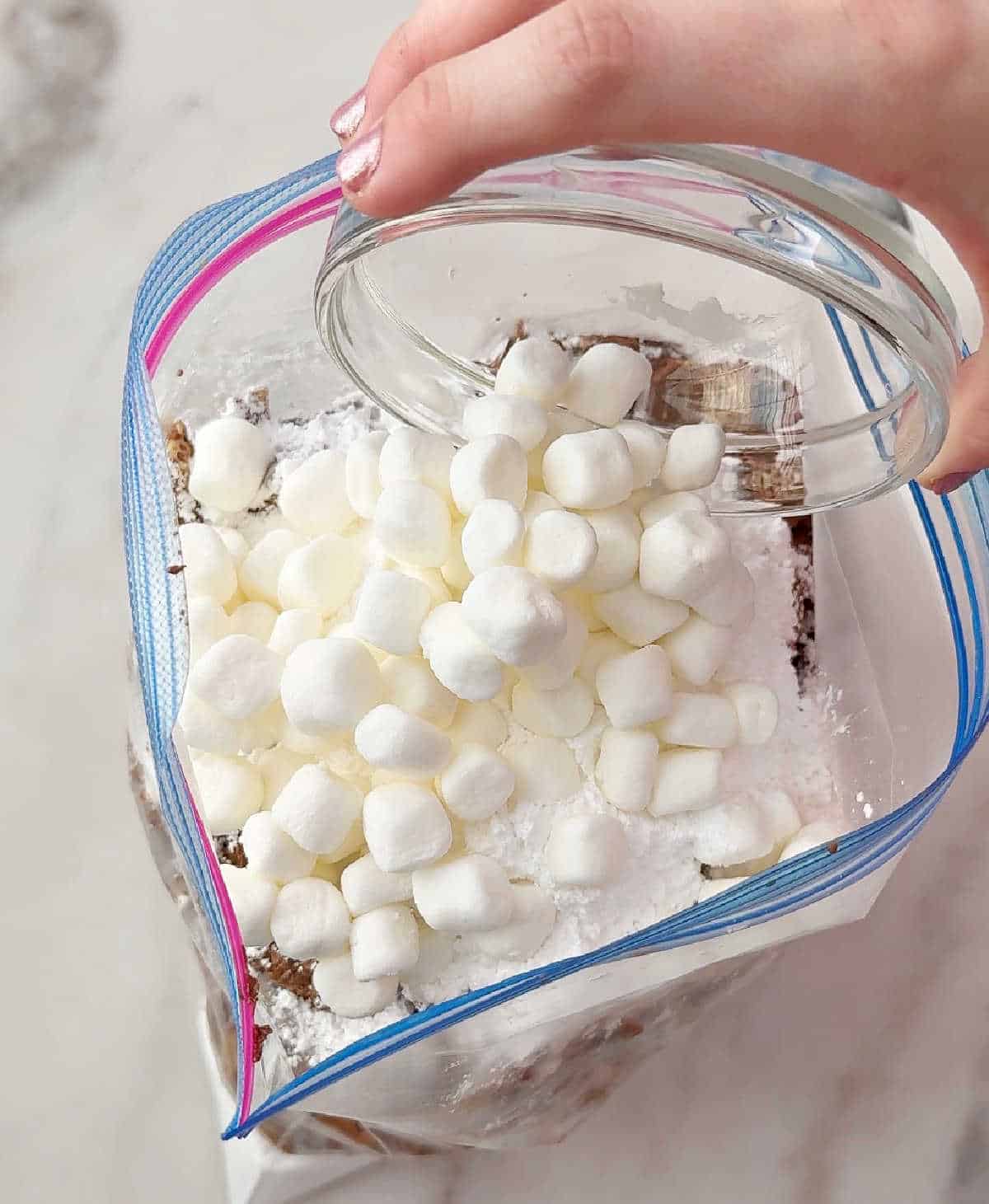 adding mini marshmallows to bag.